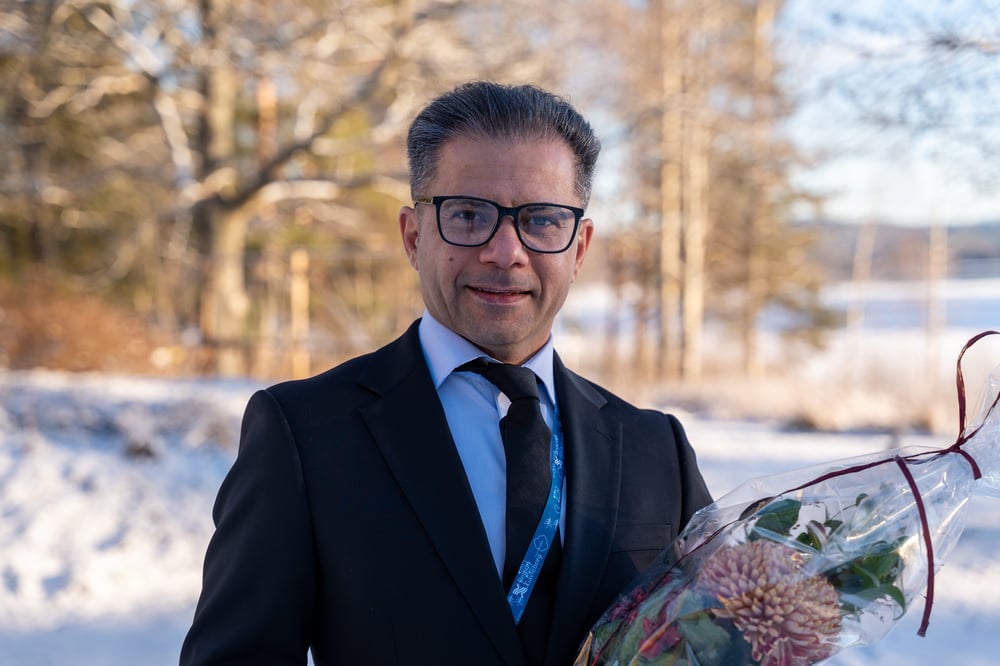Årets medarbetare, Porträtt av en person i kostym som håller en bukett blommor utomhus i vintermiljö