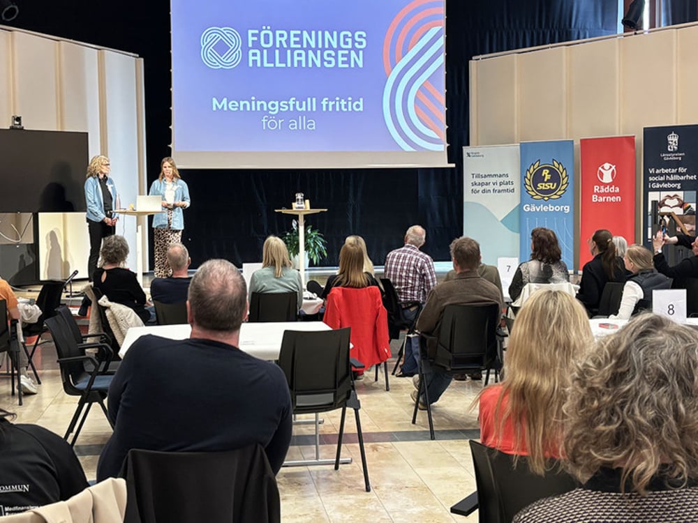 En grupp människor som sitter i stolar framför en skärm.