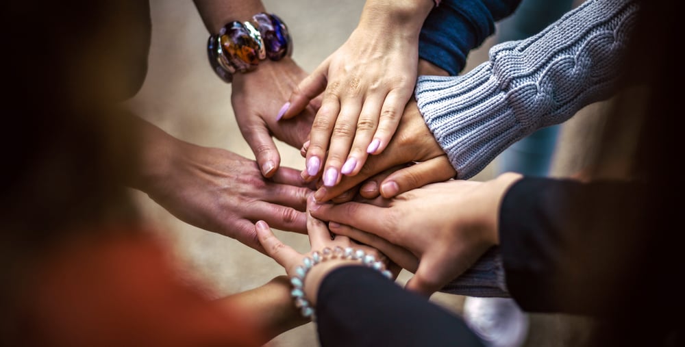 Händer som ligger ovanpå varandra sedd ovanifrån