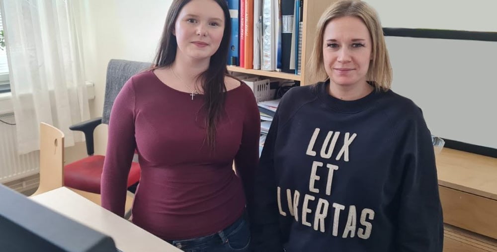 Studie- och yrkesvägledare Julia Wennbergen och hennes elev Tuva Kjellén Strandberg ståendes vid en dator inne på ett kontor