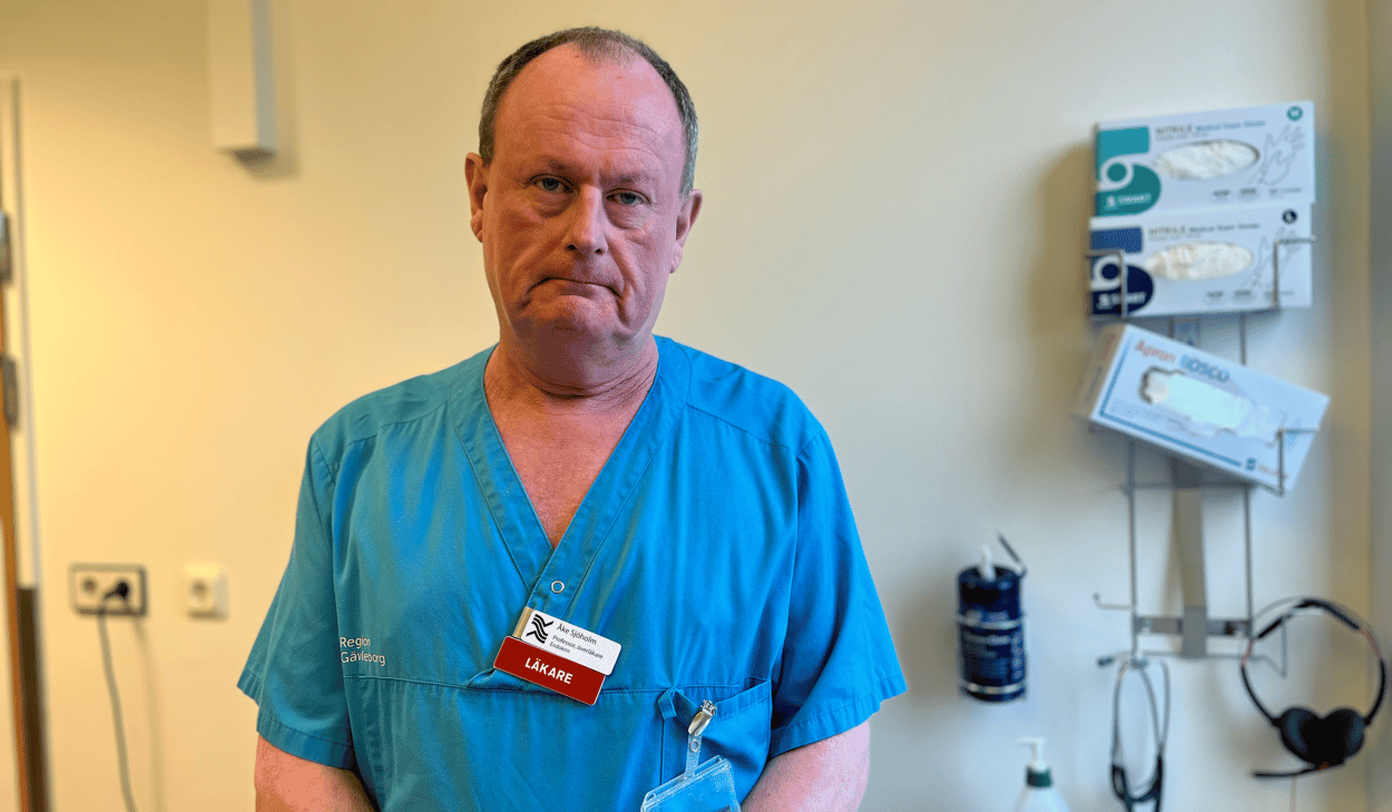 Man med blå skjorta vita byxor, står och ser i kameran, kort mörkt hår, medelålders