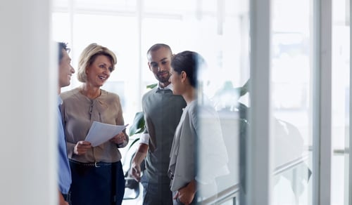 Smiling businesswoman discussing over document with colleagues in office