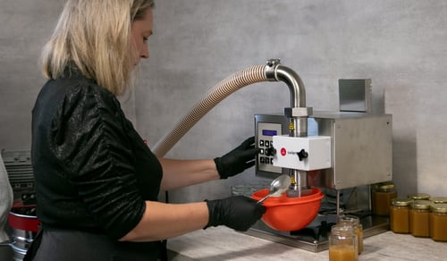 Kvinna tappar honung på burk.